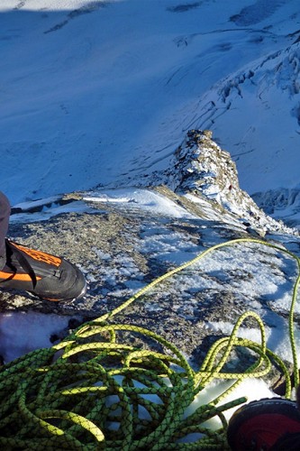 Blick hinab von einem mit Schnee bedeckten Berg.
