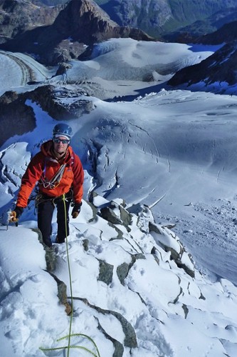 Hochtourengeher mit Hochtourenausr&uuml;stung steht an einem Berghang hinauf zum Gipfel des Piz Pal&uuml;.