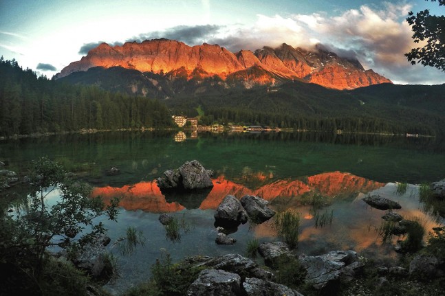 Der Eibsee (973 Meter) bei Grainau gilt aufgrund seiner Lage unterhalb der Zugspitze und des klaren, grün getönten Wasser als einer der schönsten Seen der Bayrischen Alpen. Zum Sonnenuntergang spiegelt sich das dunkelrot leuchtende Zugspitzmassiv im See. | Foto: Christian Greither Photography