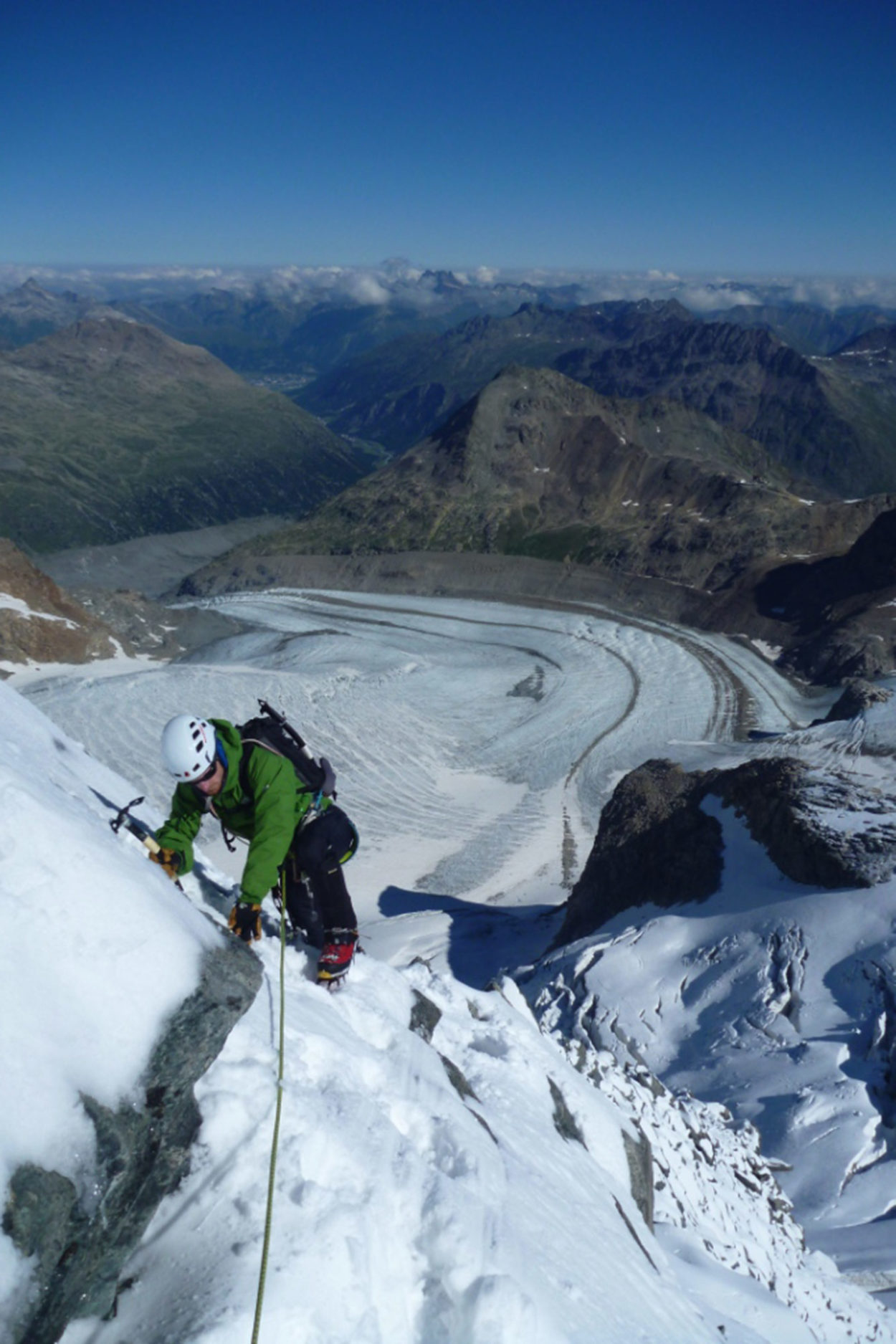 Hochtourengeher steigt mit Pickel und Steigeisen den schneebedeckten Berg Piz Pal&uuml; hinauf.