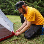 Mann spannt Befestigungspunkte am Zelt straff ab