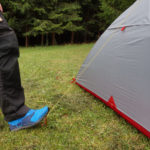 Mann dr&uuml;ckt mit Fu&szlig; auf Zelthering