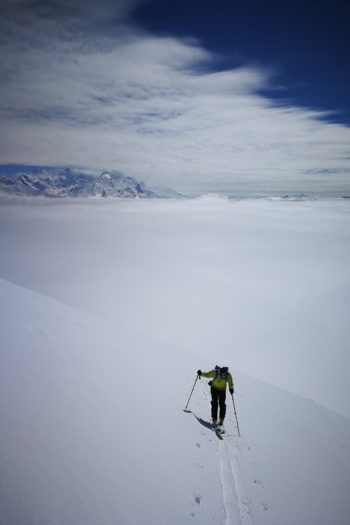 Ein Skitourengeher im Aufstieg über den Wolken.