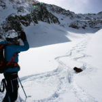 Eine Skifahrerin betrachtet ihre Abfahrtsspur im Tiefschnee.