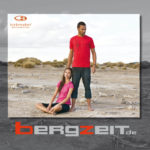 Eine Frau und ein Mann in kurzer Sommer-Freizeitkleidung in karger Wüstenlandschaft - Katalog-Cover mit Bergzeit Logo