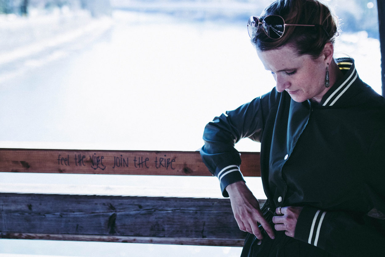 Frau lehnt an Br&uuml;ckenbr&uuml;stung in LangerChen Mantel