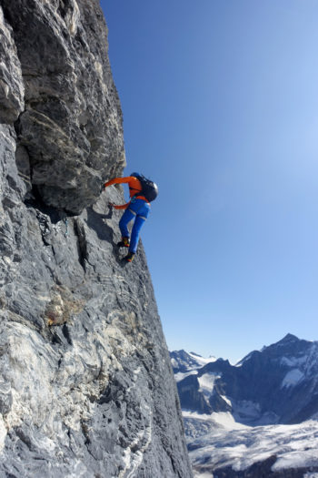 Ein Bergsteiger klettert eine Felswand entlang.