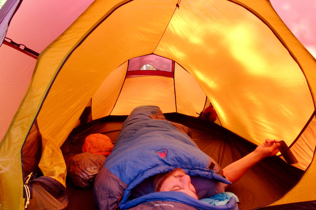 Ein Mann liegt im Schlafsack im Oppland 2 LW Zelt.