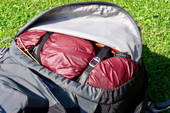 Das Zelt im Packsack mit Kompressionsriemen im Bodenfach eines Trekkingrucksacks.