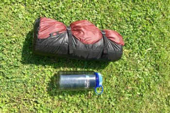 Das eingepackte Oppland 2 LW-Zelt im Packsatz, daneben eine 1-Liter-Trinkflasche von Nalgene zum Vergleich.