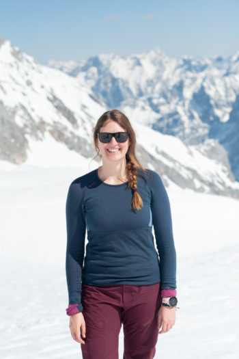 Frau in blauem Merinoshirt von Devold vor Bergapanorama